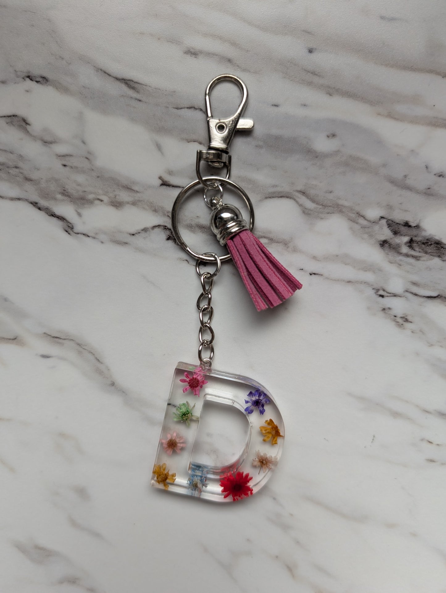 Keychain with letter 'D' and floral elements on a marble surface