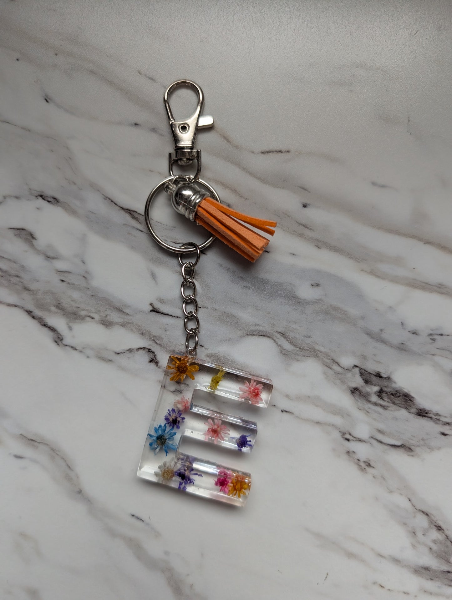Keychain with floral design and tassel on a marble surface