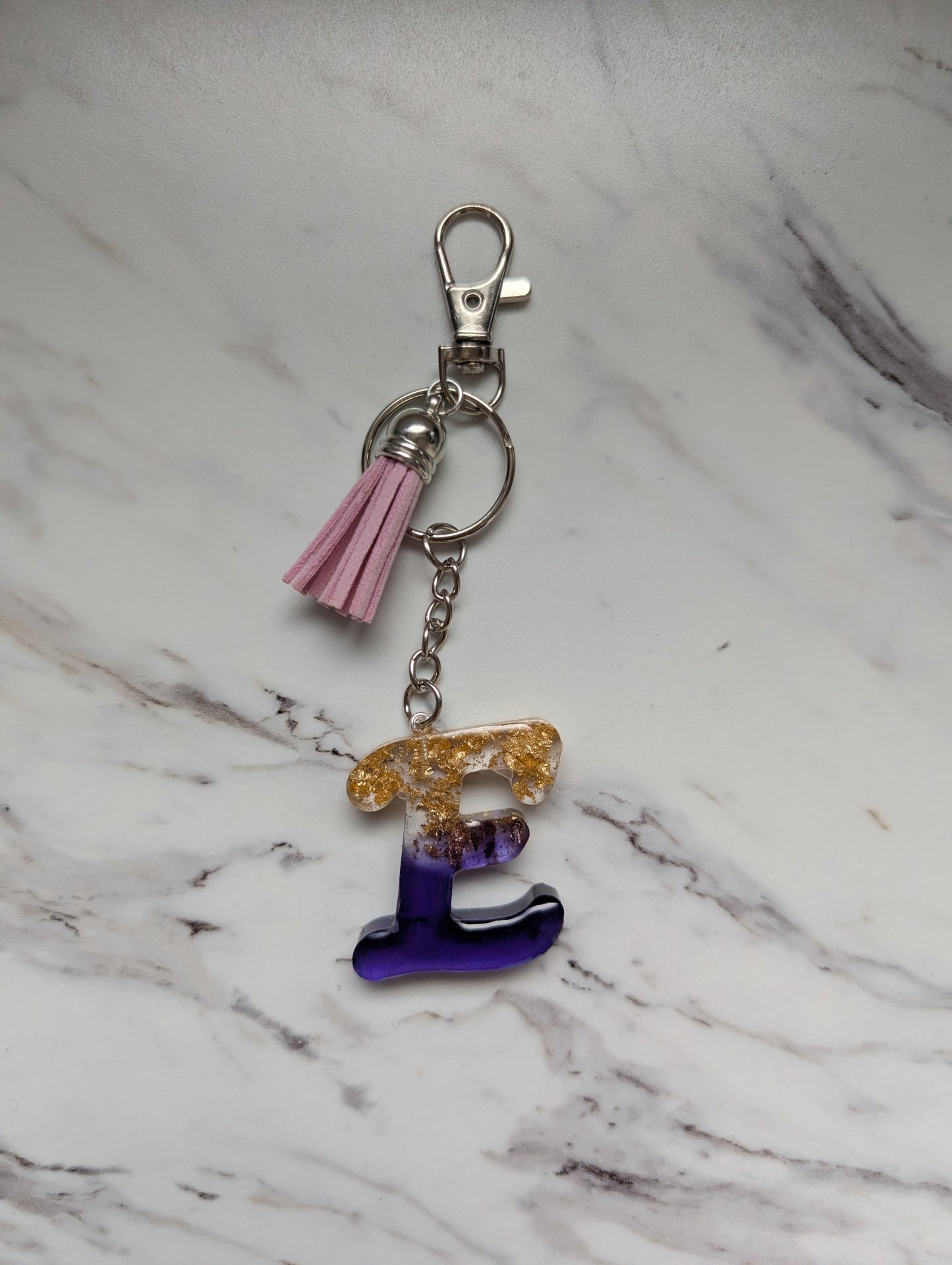 Keychain with letter 'E' charm on a marble surface