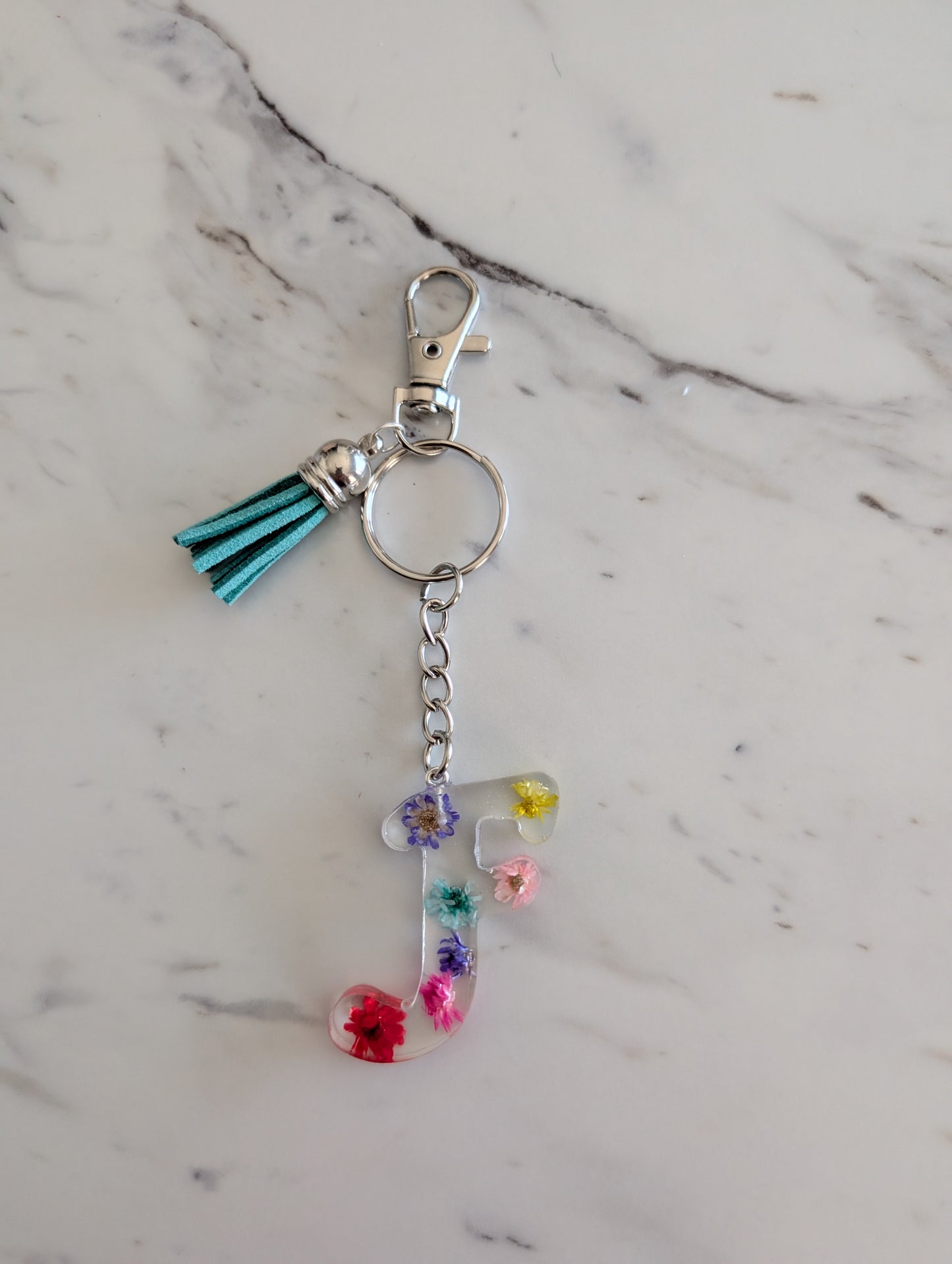 Keychain with floral letter F charm on a marble background