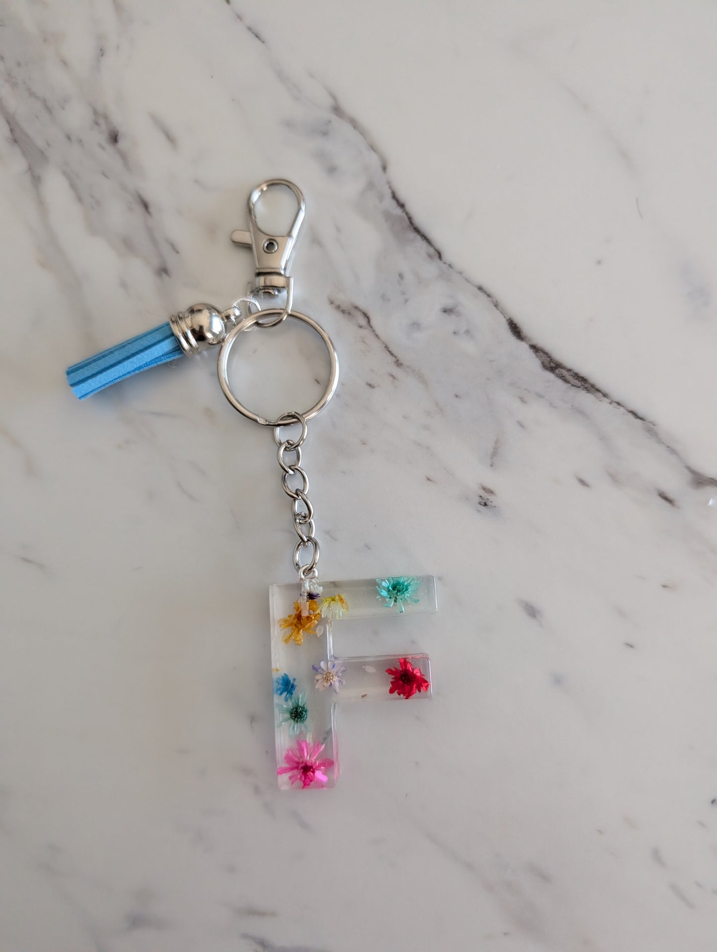 Keychain with letter 'F' and floral decorations on a marble background