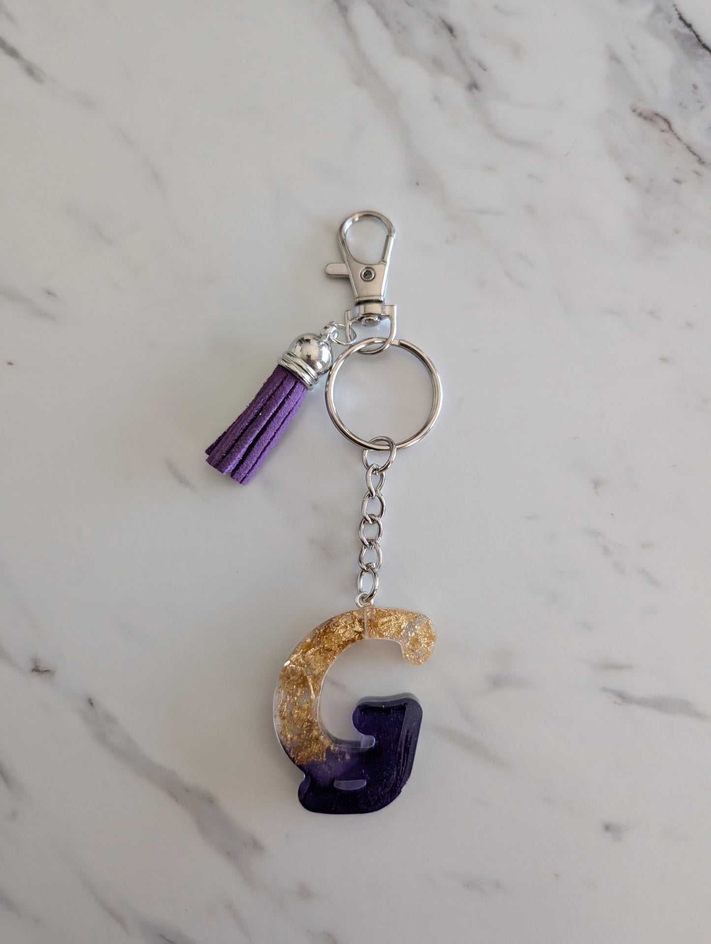Gold and purple letter G keychain with a purple tassel