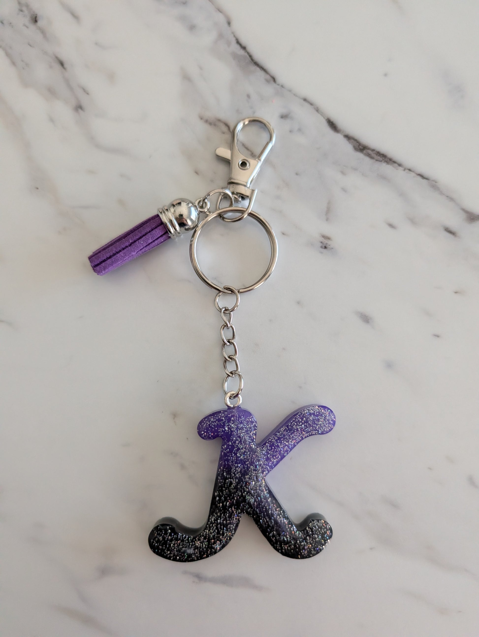 Keychain with letter 'K' in purple and black gradient on a marble background