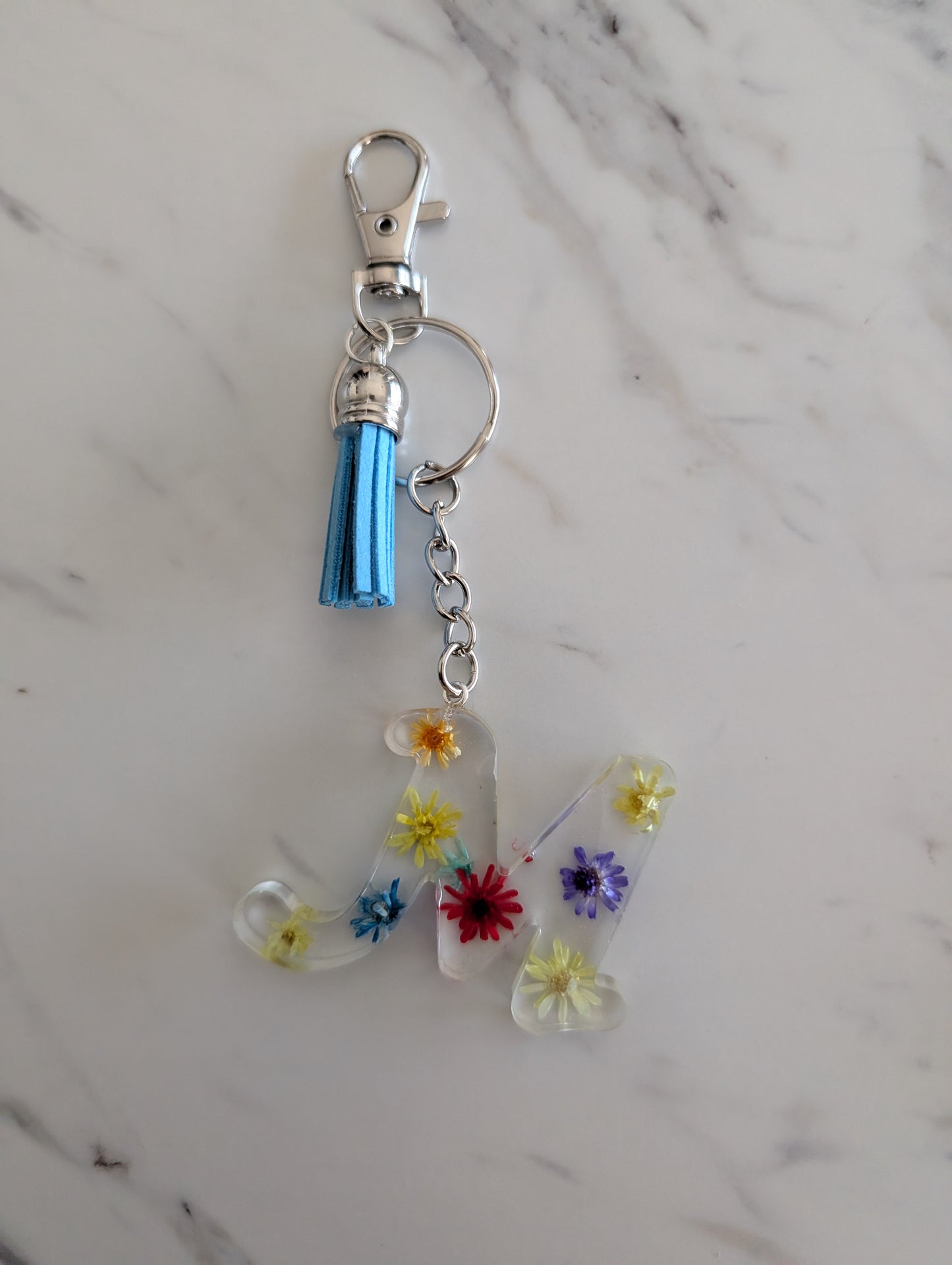 Keychain with Letter M floral charm on a marble surface