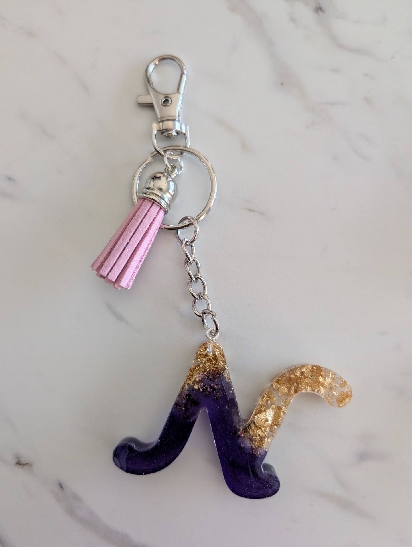 Keychain with purple and gold letter 'N' on a marble background