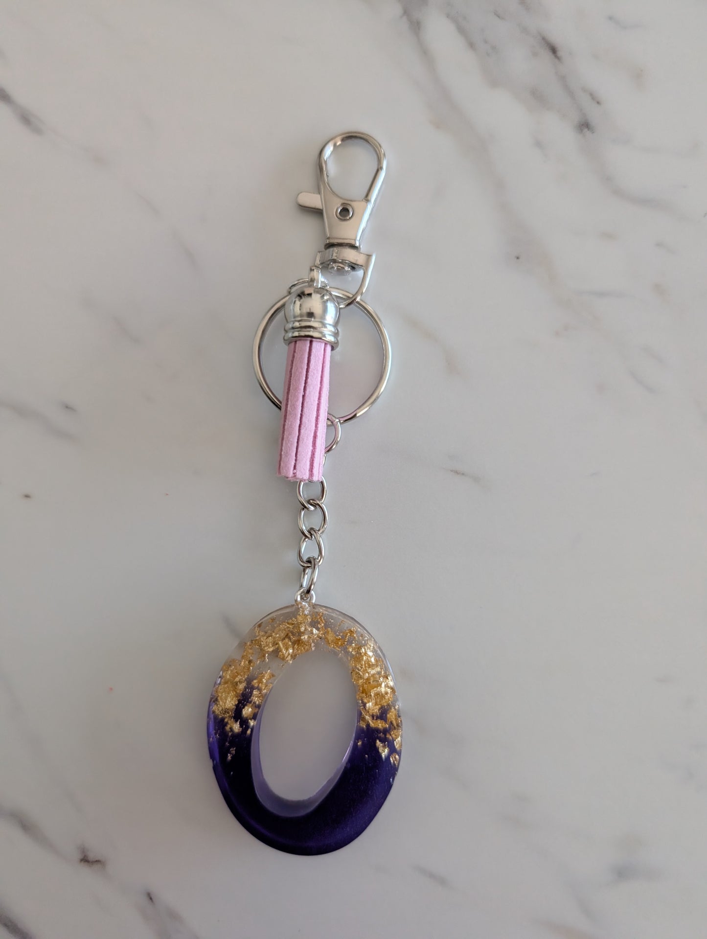 Keychain with purple and gold letter O design on a marble surface