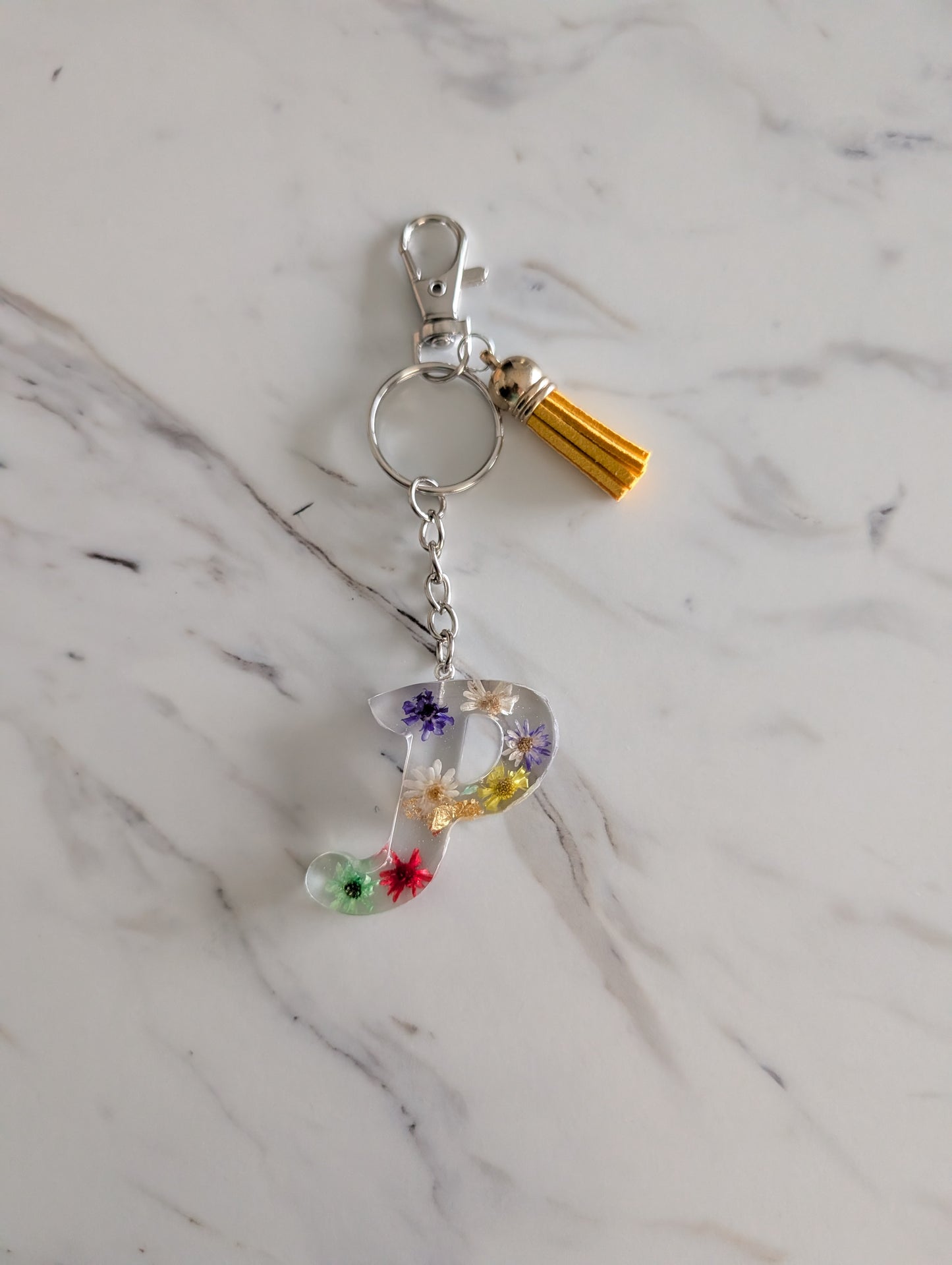 Keychain with floral letter 'P' charm on a marble background