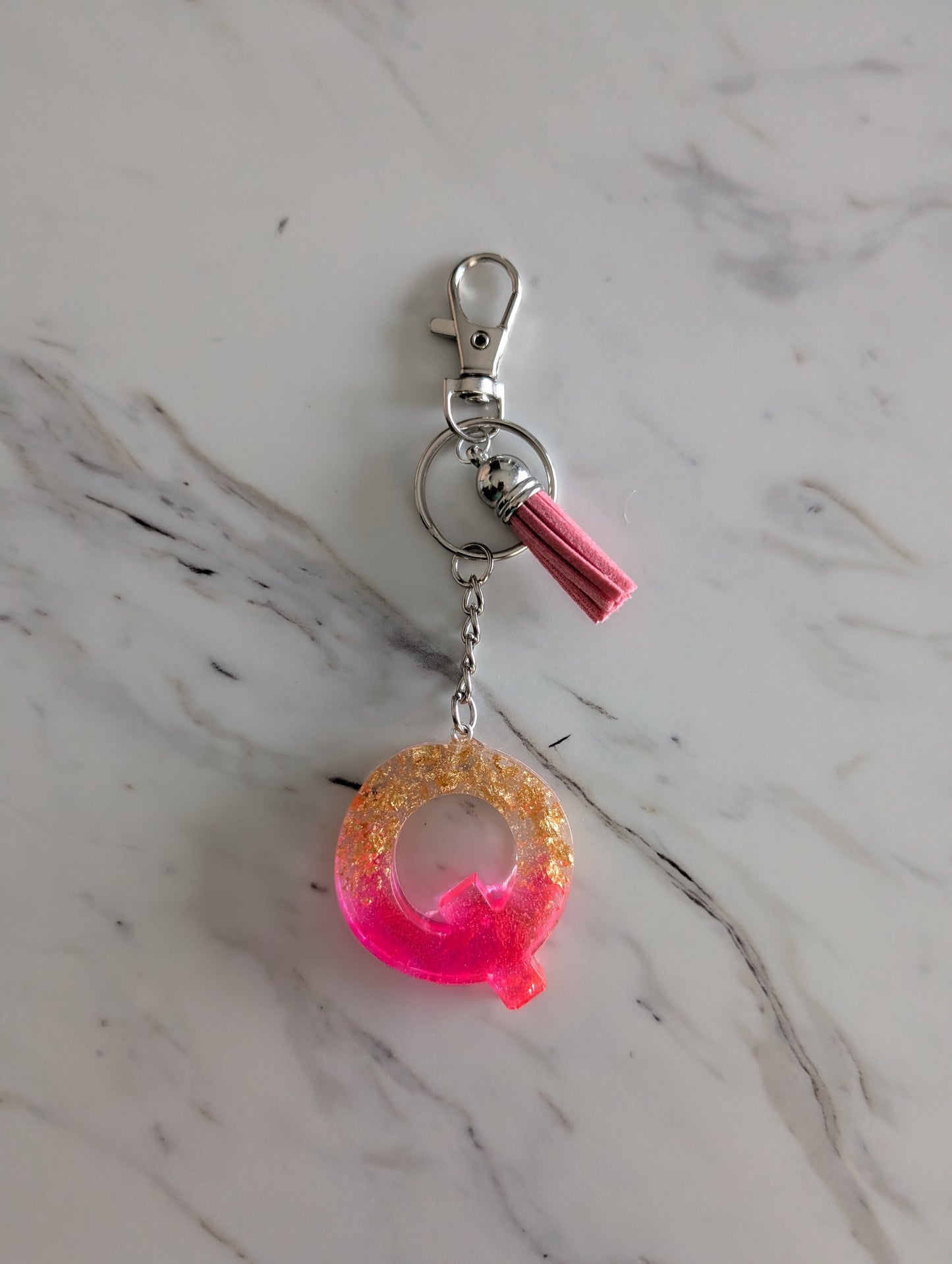 Letter Q Keychain with a pink and gold design on a marble surface