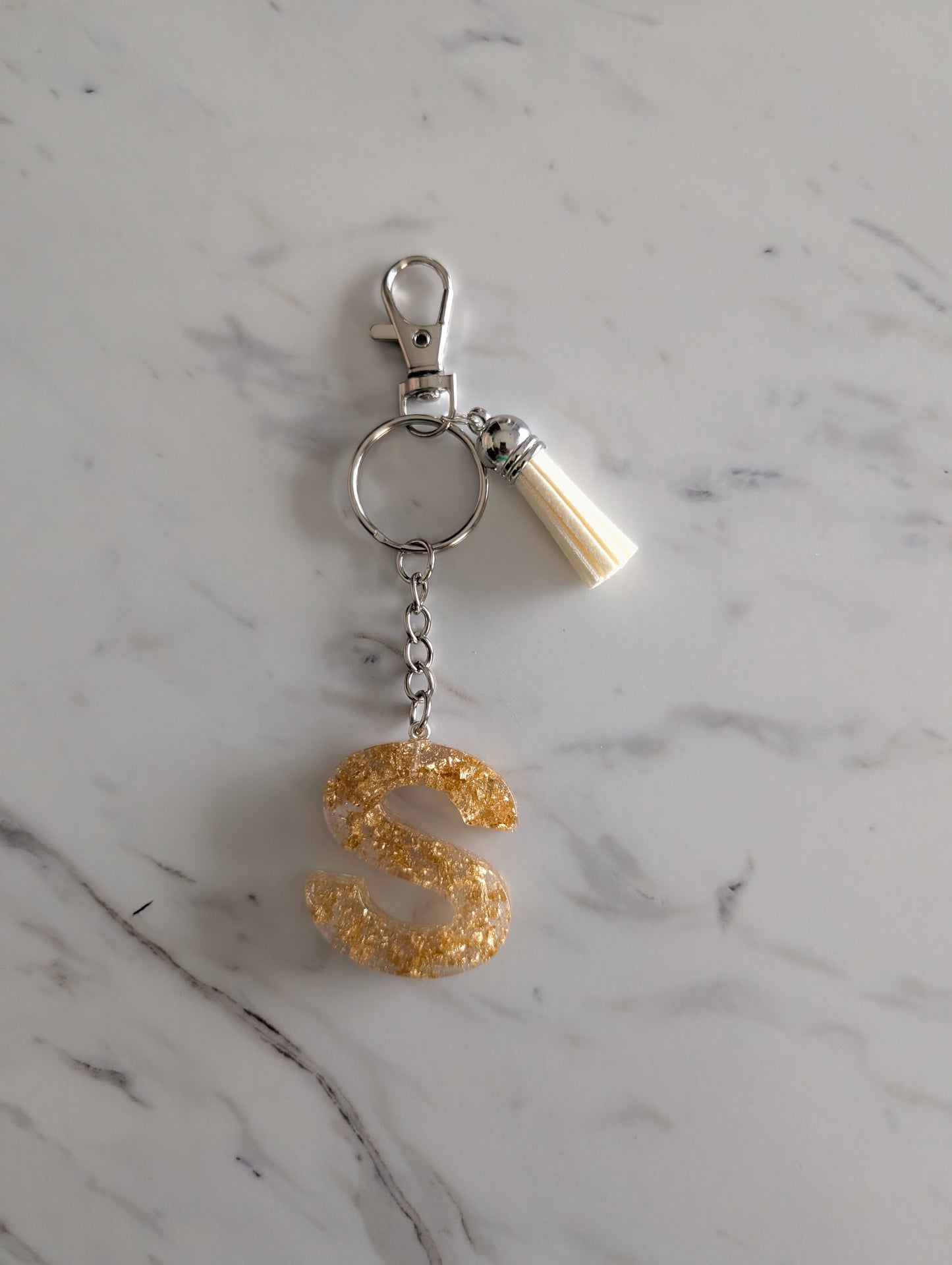 Gold letter 'S' keychain on a marble surface