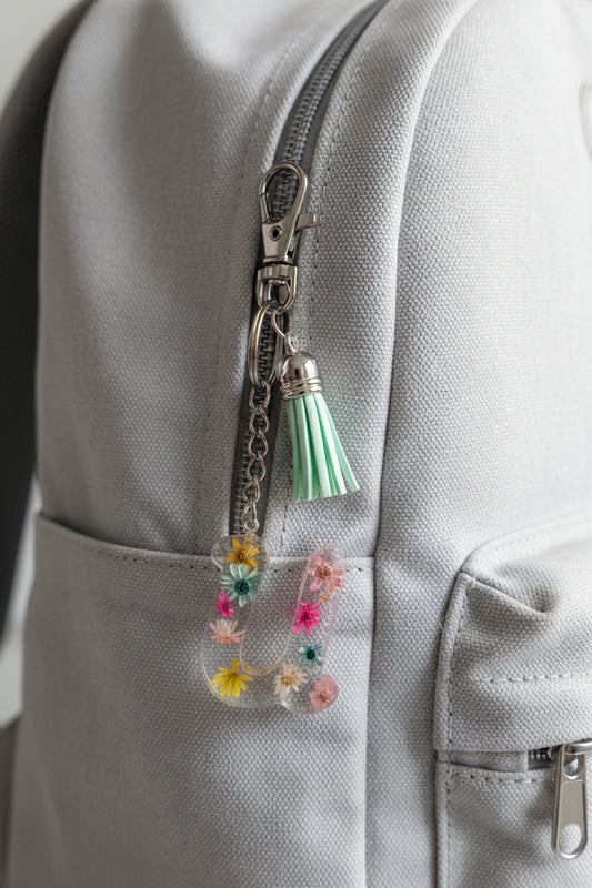 Letter U Decorative keychain with colorful flowers and a green tassel on a backpack