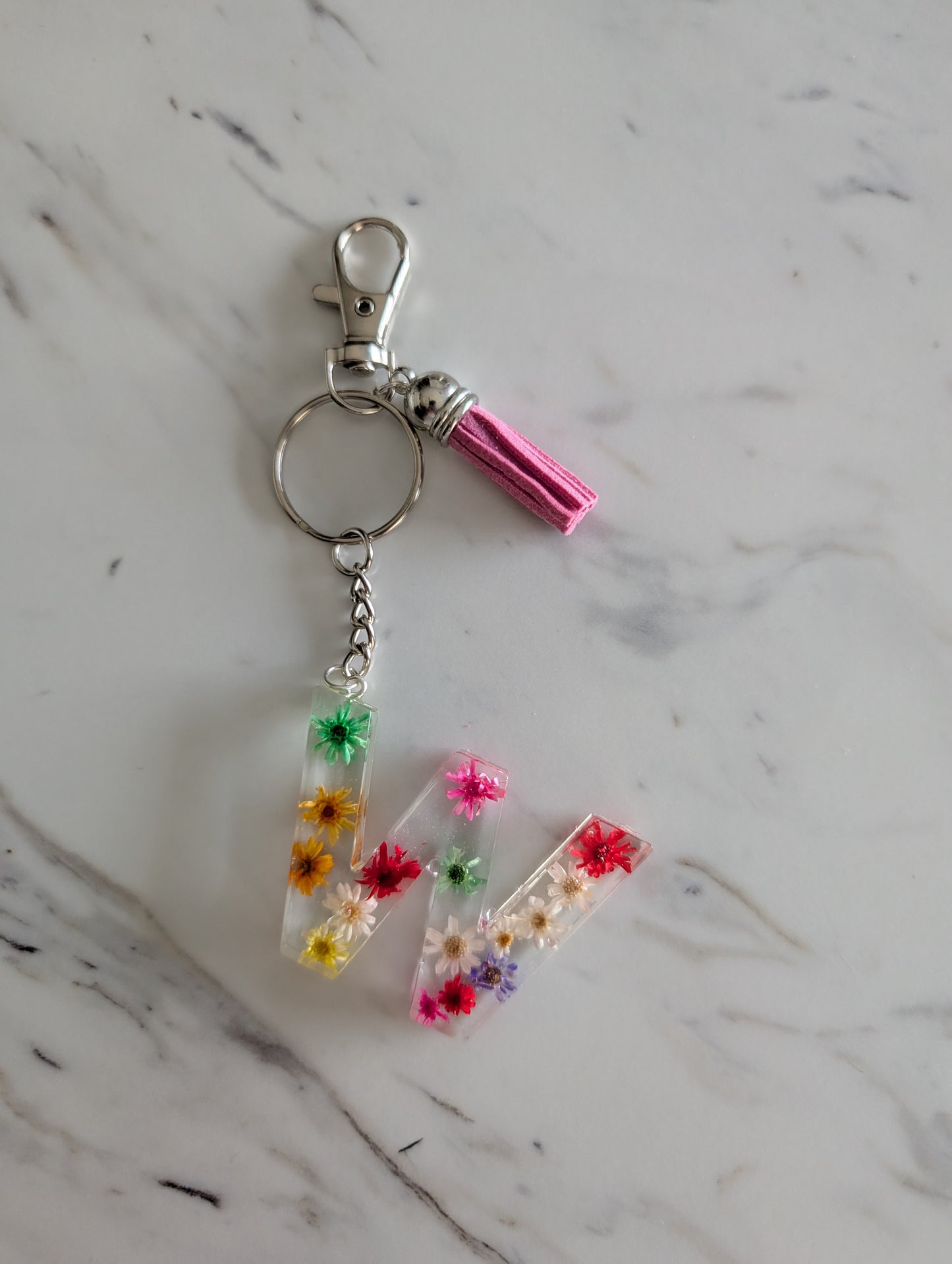 Keychain with floral letter 'W' charm on a marble surface