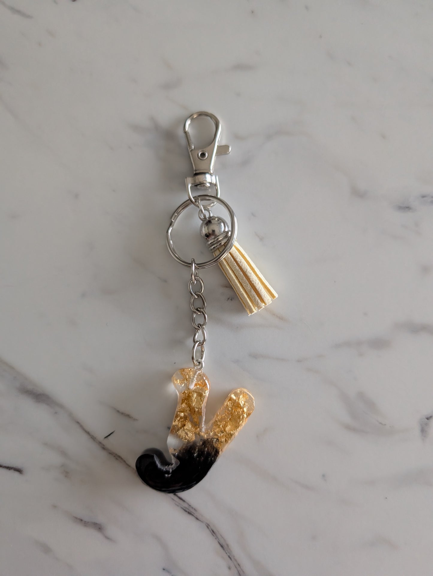 Gold and black letter Y Keychain on a marble surface