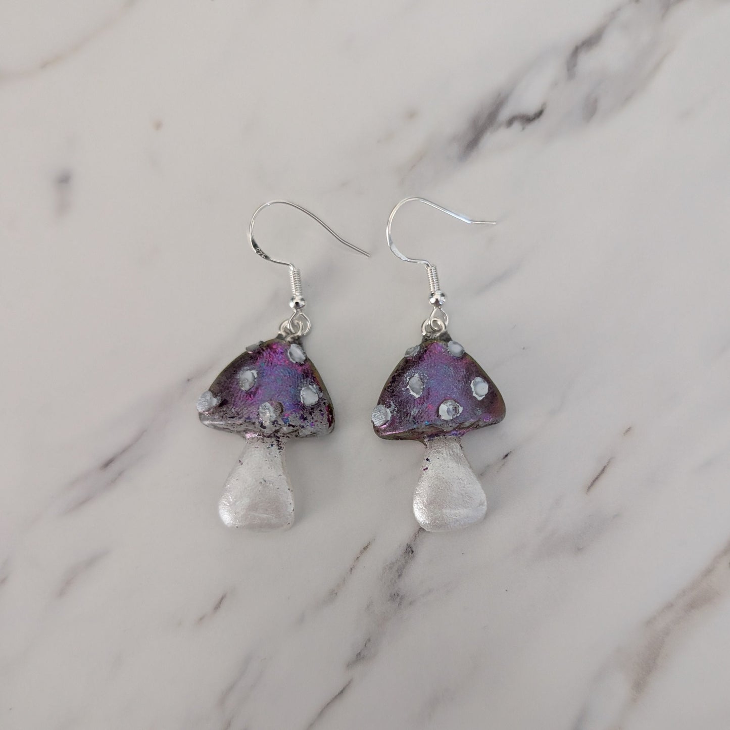 Purple mushroom-shaped earrings on a marble surface