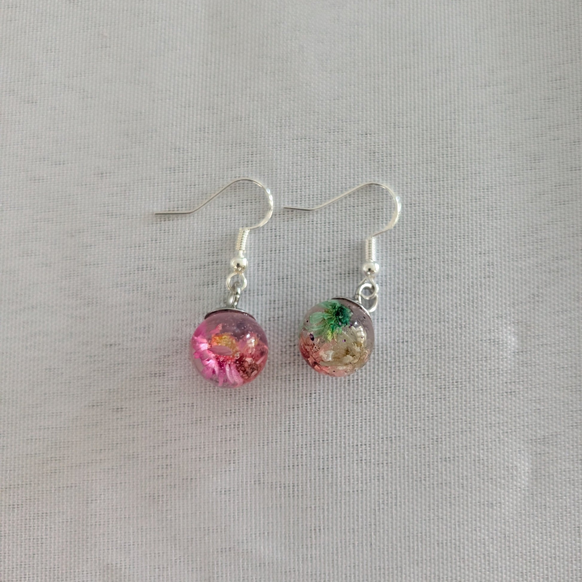 Pair of earrings with colorful round beads on a light gray background