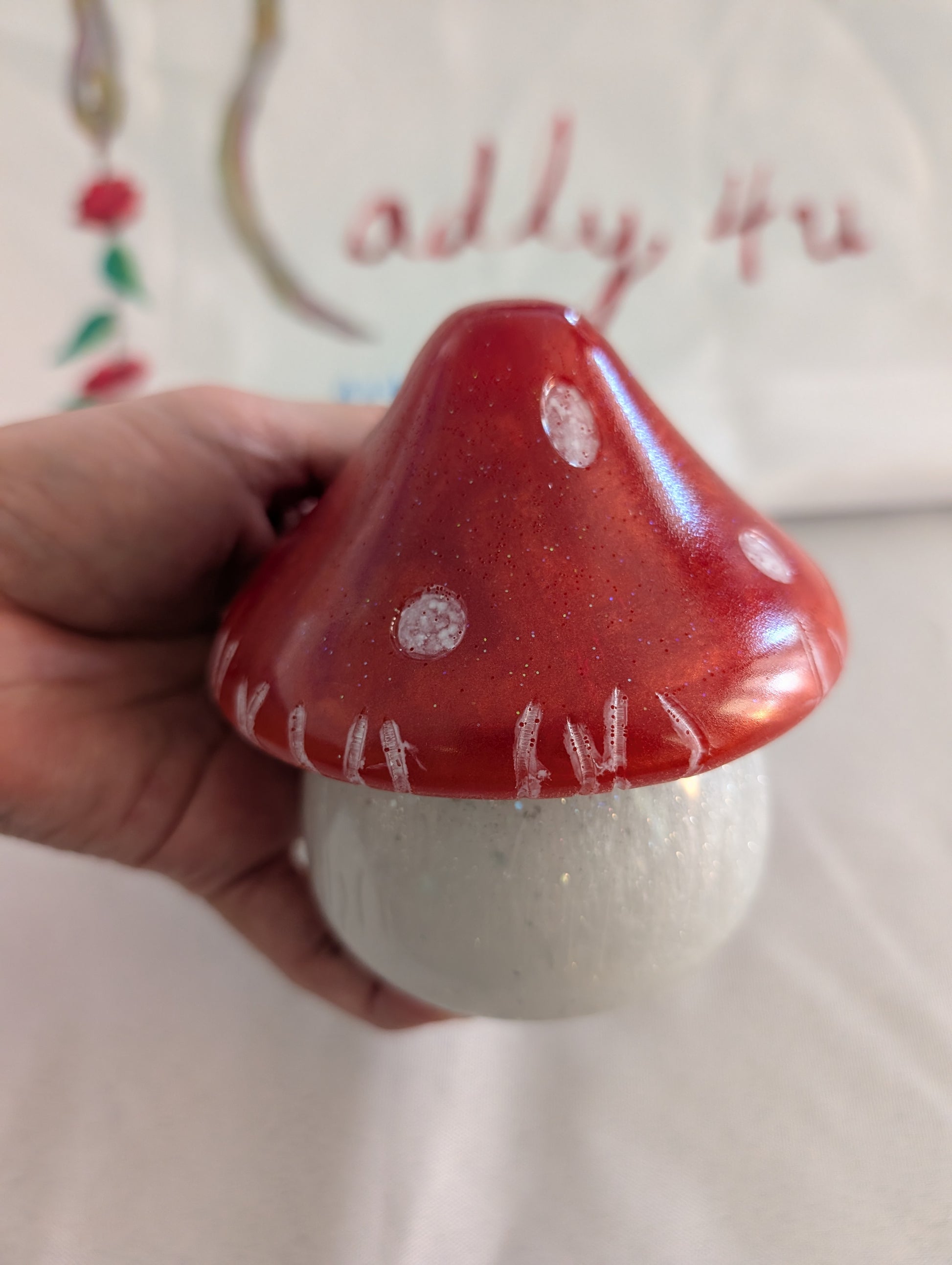 This charming hand-crafted resin mushroom trinket brings whimsical elegance to any space. Meticulously sculpted from epoxy resin, it features a smooth, glass-like finish that's both durable and non-porous—perfect for storing small treasures, jewelry, or keepsakes. The removable lid makes access effortless, while its compact 4.5-inch height and 4x4-inch width fit seamlessly on shelves, desks, or nightstands. At just 12.4 ounces, it's lightweight yet substantial enough to feel premium. Each piece showcases th