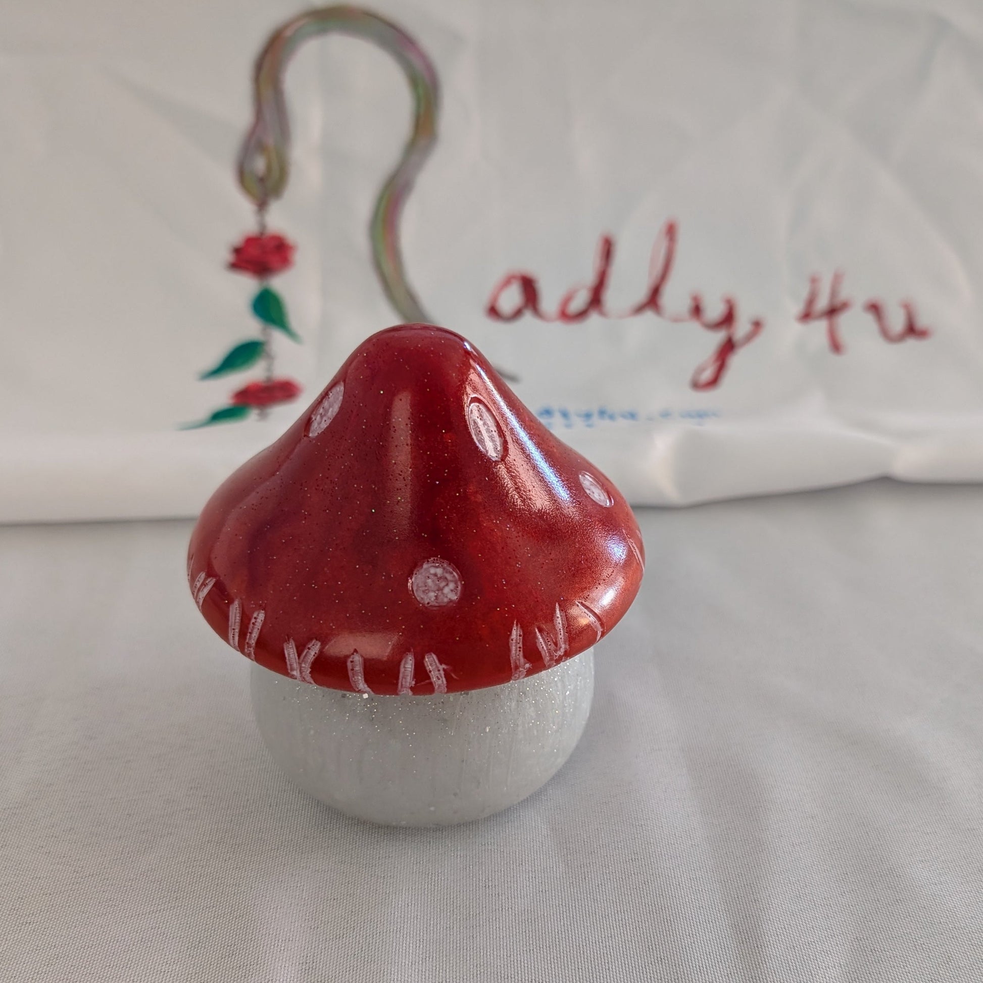 This charming hand-crafted resin mushroom trinket brings whimsical elegance to any space. Meticulously sculpted from epoxy resin, it features a smooth, glass-like finish that's both durable and non-porous—perfect for storing small treasures, jewelry, or keepsakes. The removable lid makes access effortless, while its compact 4.5-inch height and 4x4-inch width fit seamlessly on shelves, desks, or nightstands. At just 12.4 ounces, it's lightweight yet substantial enough to feel premium. Each piece showcases th