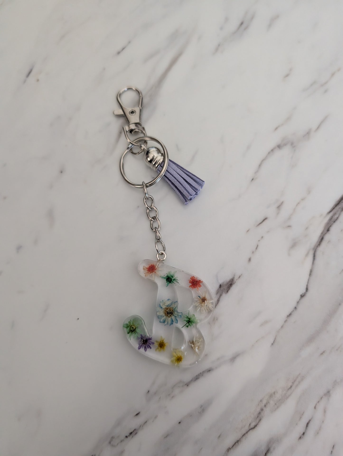 Keychain with floral letter 'B' charm on a marble surface