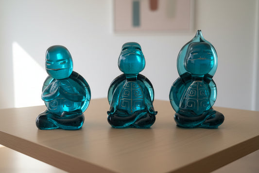 Three blue resin turtle statues on a table with a blurred indoor background.