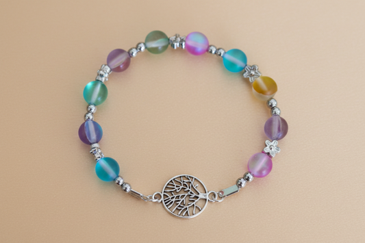 Multicolored beaded bracelet with a silver tree of life charm on a beige background