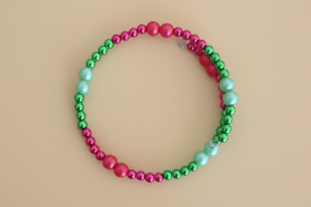 green and red beaded bracelet on a beige background
