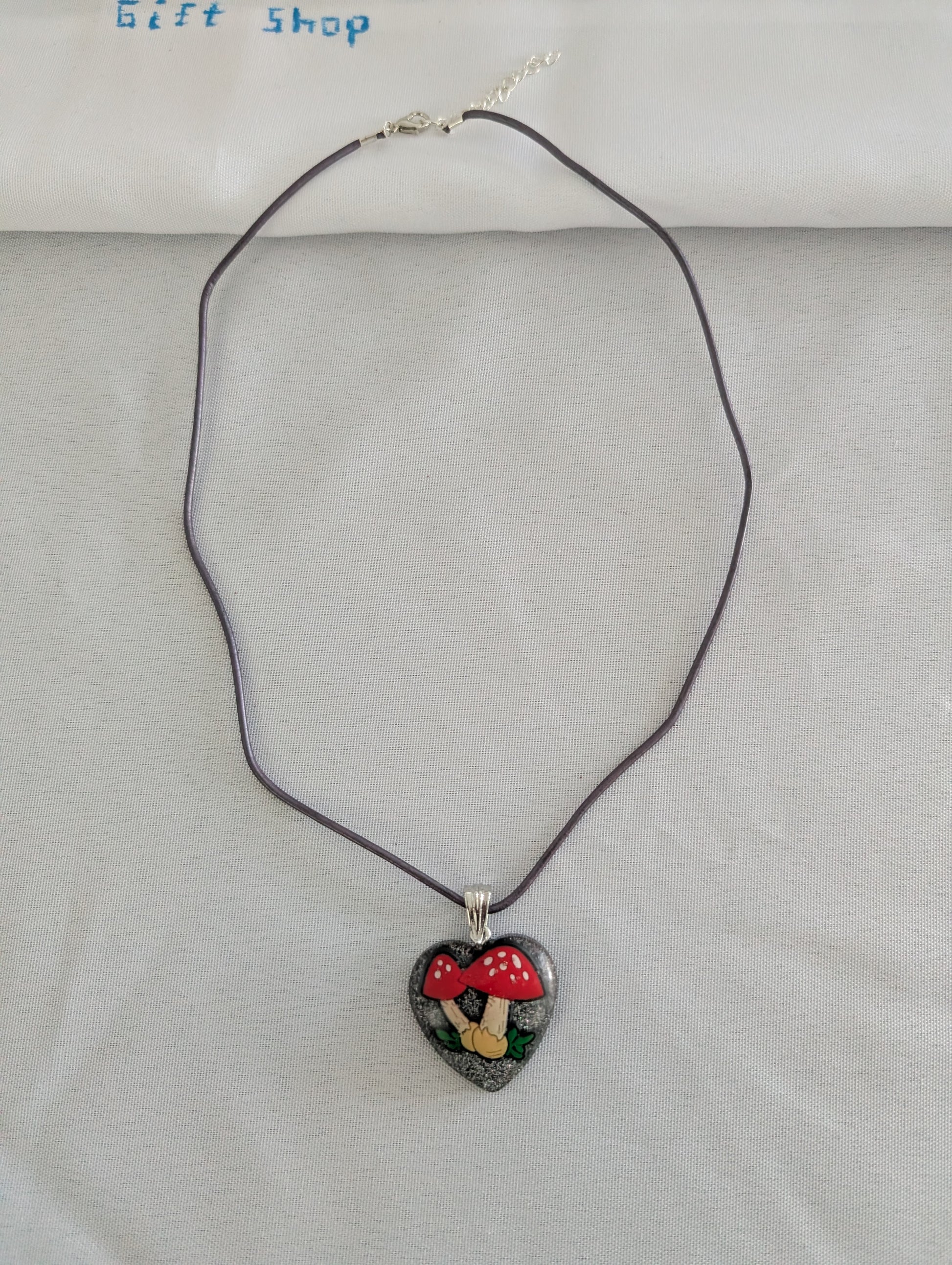 Heart-shaped pendant necklace with a mushroom design on a gray background