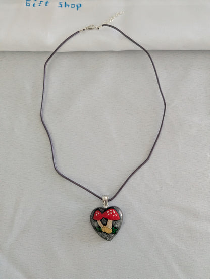 Heart-shaped pendant necklace with a mushroom design on a gray background