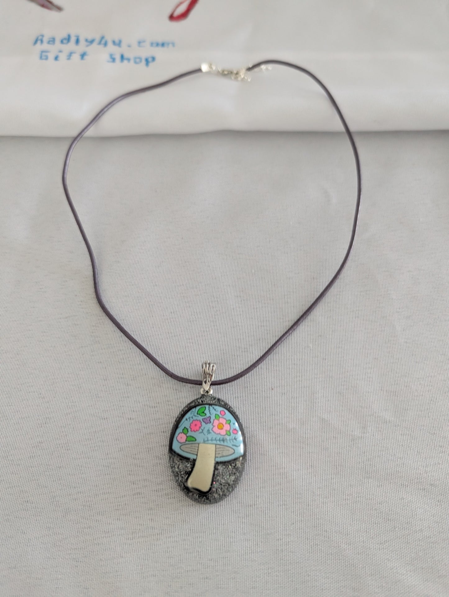Necklace with a pendant featuring a mushroom design on a gray background